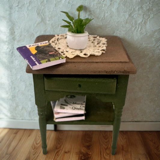 Green side table with a wooden top, books, and a plant against a light blue wall.