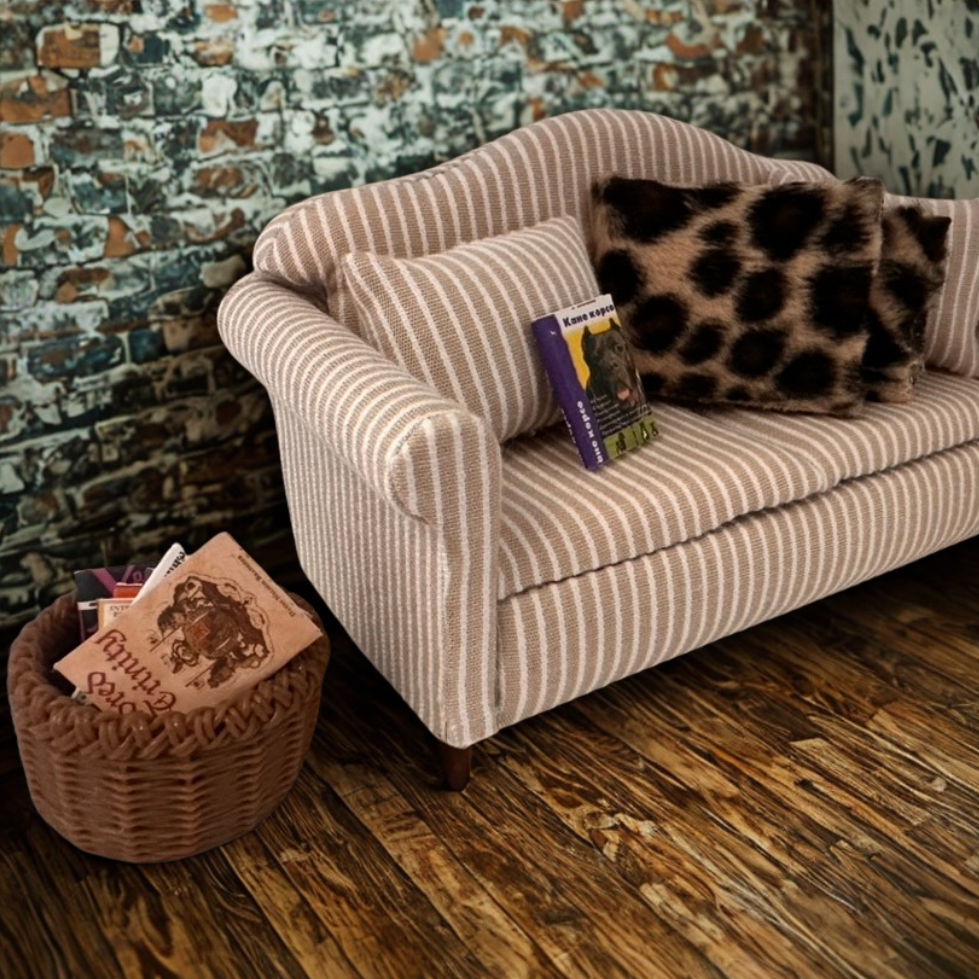 Books on a striped sofa with decorative pillows against a textured wall.